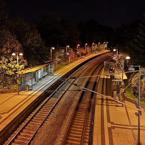 Bahnlinie mit Haltestelle, nachts. Symbolbild.